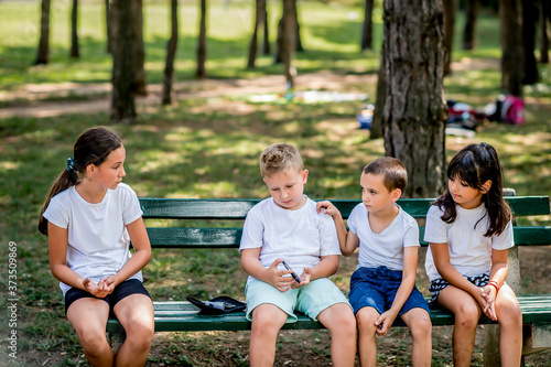 School boy with diabetes testing his blood sugar after physical education, friends support him.