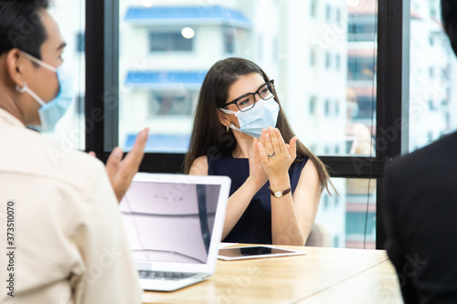 Young businesswoman and business man wearing protective face mask while meeting for making new business plans during COVID-19 pandemic