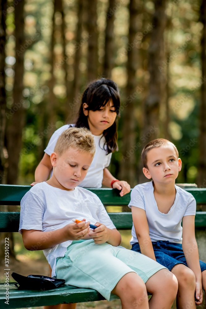School boy with diabetes testing his blood sugar after physical education, friends support him.