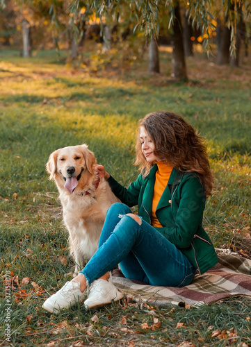Golden retriever dog with a curly woman walking outdoors on sunny day. Training the dog in the park. love and care for the pet. 
