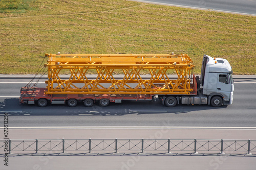 Transportation of tower crane components on pltaform truck trailers along the highway. photo