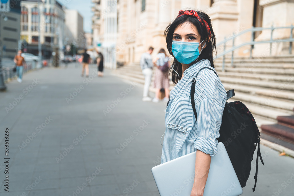 Female student wearing protective face mask walking around college during pandemic