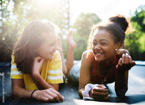 Front view of young teenager girls friends outdoors in garden, laughing.
