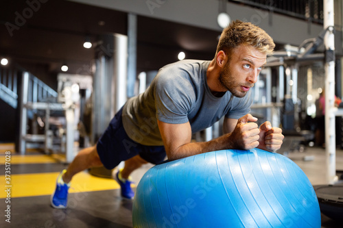 Fit man doing fitness exercise on pilates ball in gym