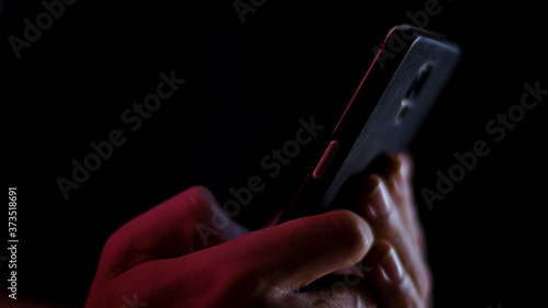 Hand using a smart phone in close up on a black background	
