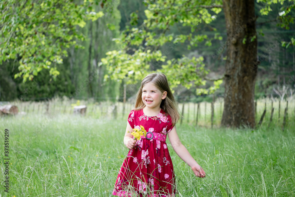 Young girl walking through long green grass holding yellow flowers Young girl walking through long green grass holding yellow flowers
