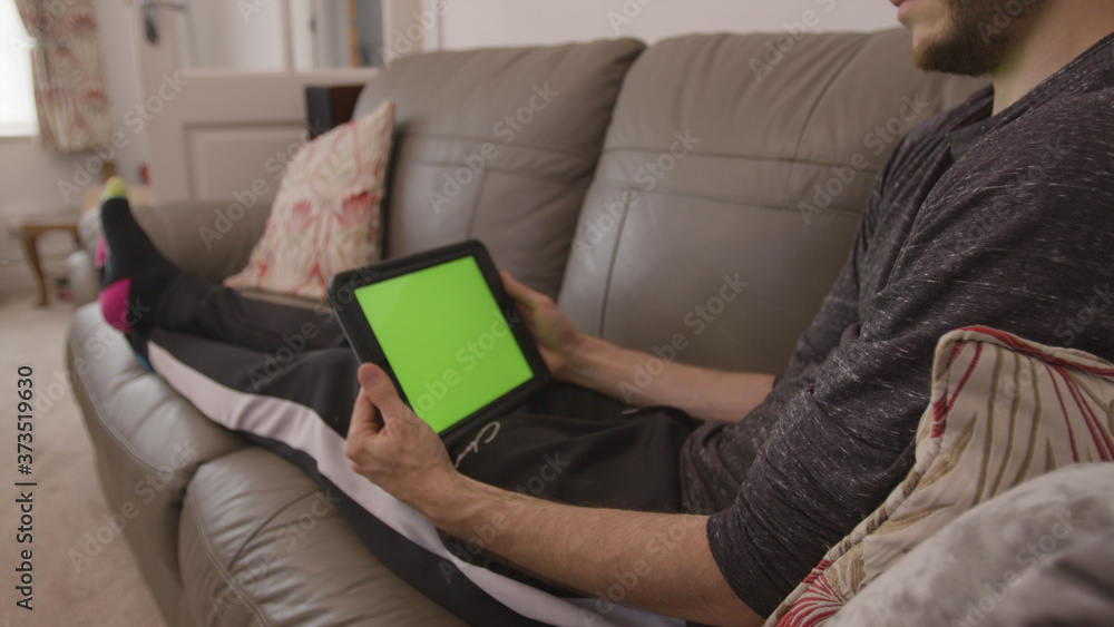 Male professional using a green screen tablet while working from home living room Male professional using a green screen tablet while working from home living room