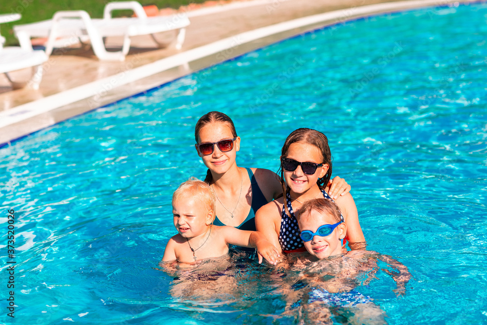 Happy children having fun at the pool during summer vacation.