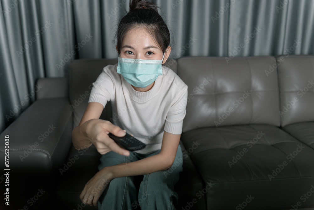 Young Asian woman wearing a mask to prevent coronavirus infection.And being on the sofa in the house