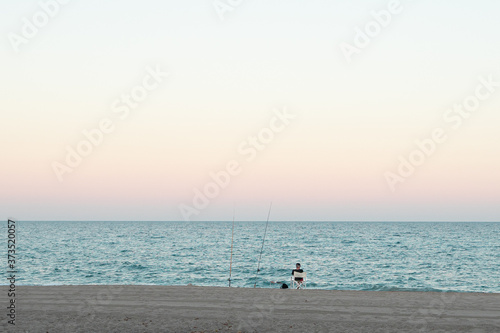 A man fishing on the beach at sunset