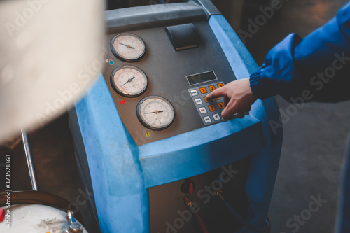 mechanic presses a button on the machine to refuel air conditioners photo