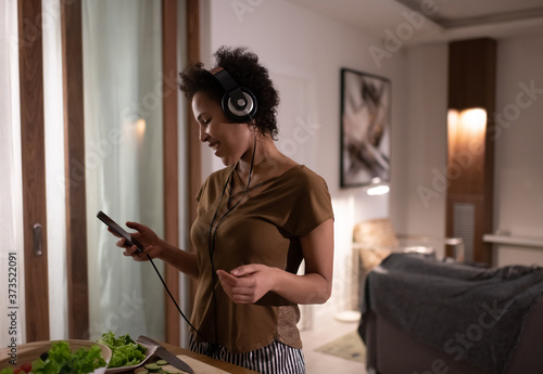 Mixed race female listening to music while cooking photo