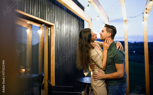 Young couple dancing outdoors at dusk, weekend away in container house in countryside.