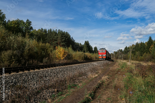 Red old train rides by rail among the forest in summer