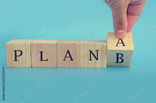 Time for Plan B. Hand is turning a cube and changes the word 'Plan A' to 'Plan B'.. Business concept. Copy space.Beautiful blue background.