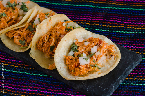 Mexican tacos filled with tinga de pollo on a traditional textile background photo