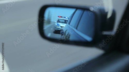 Yerevan, Armenia - June 2020 - Police car in the side mirror chasing a car on highway. Police chase, the car is running away from the chase