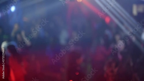 crowd of people dancing on the dance floor of a night club under the light of colored spotlights and lasers