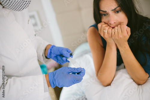 The female doctor in protective equipment a mask, gloves performs the vaccination procedure. Human vaccination process against coronavirus. Female scared getting an injection from a doctor.