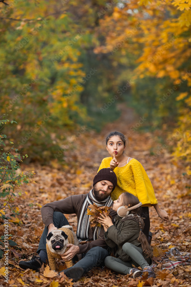 bearded dad with daughters and a dog in the leaves in autumn in the park bearded dad with daughters and a dog in the leaves in autumn in the park