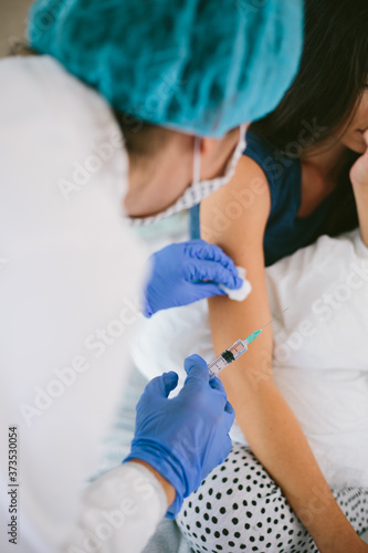 The female doctor in protective equipment a mask, gloves performs the vaccination procedure. Human vaccination process against coronavirus. Female scared getting an injection from a doctor.