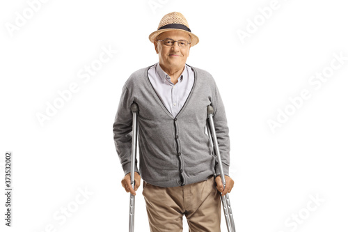 Foto Elderly man walking with crutches and smiling at the camera