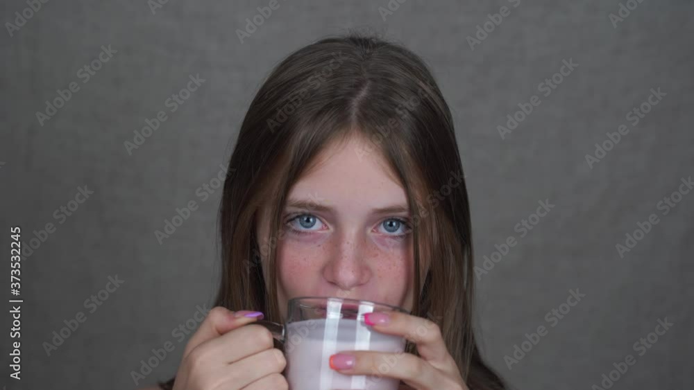 Young girl drinking strawberry yogurt from a glass, close up. Studio portrait. Diet and nutrition. Healthy dieting. Dairy products Young girl drinking strawberry yogurt from a glass, close up. Studio portrait. Diet and nutrition. Healthy dieting. Dairy products