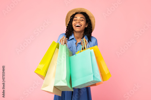 African Woman Laughing Holding Shopper Bags On Pink Studio Background