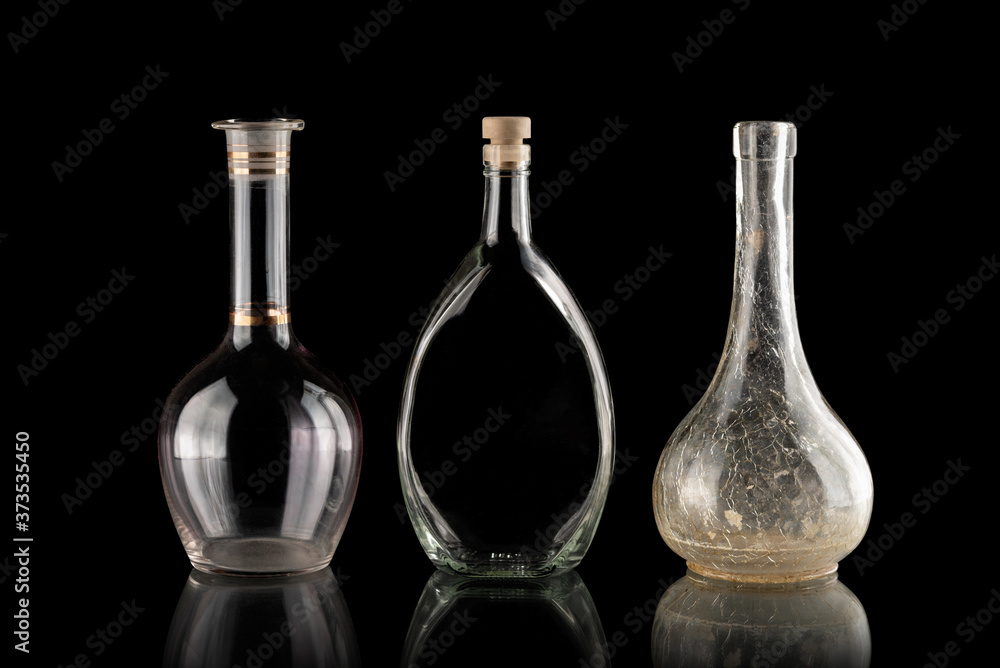 Glassware on a black isolated background. Decanters of various shapes. A group of transparent items. The reflection under the objects. Old household items. Fragile dishes. Liquid containers. Glassware on a black isolated background. Decanters of various shapes. A group of transparent items. The reflection under the objects. Old household items. Fragile dishes. Liquid containers.