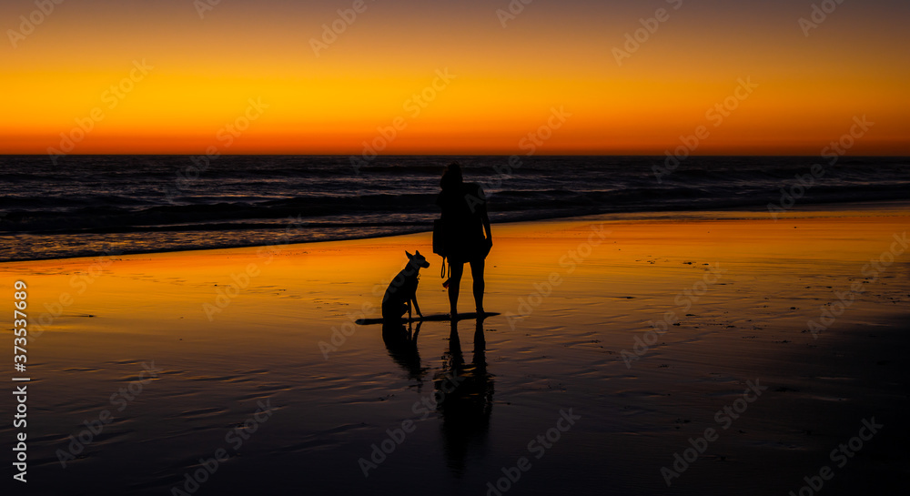 Women with her dog walking on the beach of El Palmar in cadiz at sunset