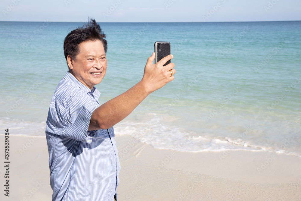 Asian Senior Man Take Selfie on His Mobilephone on the Beach Asian Senior Man Take Selfie on His Mobilephone on the Beach
