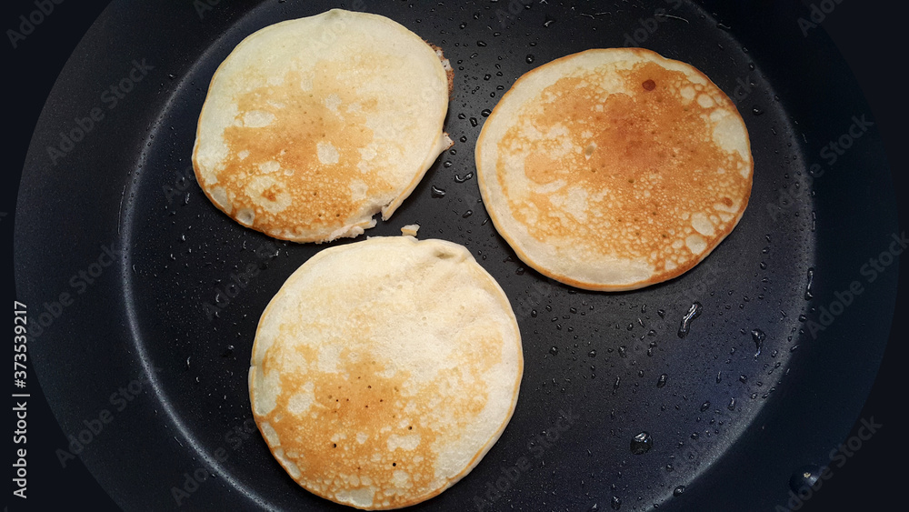 Delicious thin pancakes on a non-stick pan. Top view. Flat lay. Cooking process. Pancakes recipe. Delicious thin pancakes on a non-stick pan. Top view. Flat lay. Cooking process. Pancakes recipe.