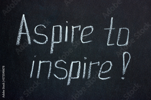 Chalk lettering on a dark board exclamation Aspire to inspire. Motivating phrase