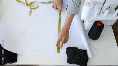 Young woman tailor is designing a new dress in her mini workshop.