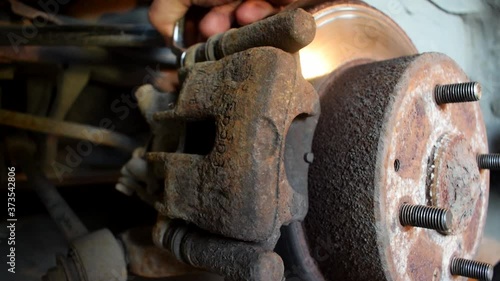 Closeup of a rusted brake caliper, attempting to unbolt it