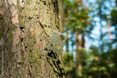 A multi-tool made from a single sheet of metal is stuck into the wood.