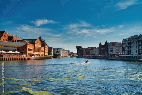 Gdansk, North Poland - August 13, 2020: Panoramic view of summer in motlawa river adjacent to beautiful european architecture near baltic sea during covid 19 pandemic against blue sky © Arpan