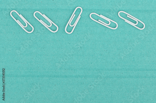 Teal textured cardboard with paperclips closeup background