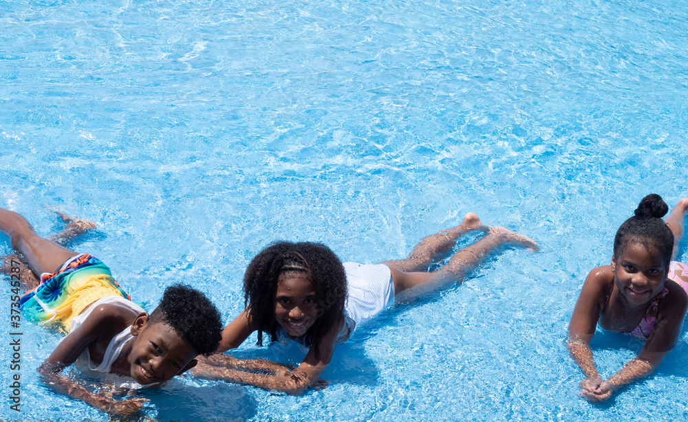 Summer season. Three African American children having fun on the swimming pool in aqua park at the day time. Fun and summer lifestyle. Summer season. Three African American children having fun on the swimming pool in aqua park at the day time. Fun and summer lifestyle.