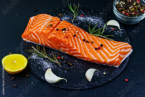 Raw salmon fillet with spices on black slate