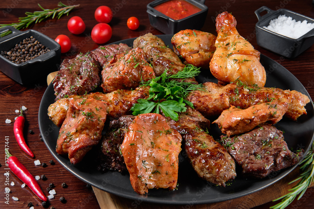 Assorted delicious grilled meat with vegetable. Mixed grilled bbq meat with vegetables. Set of shish kebabs or barbecue shashlik collection. Baked potatoes and fresh tomatoes. 
