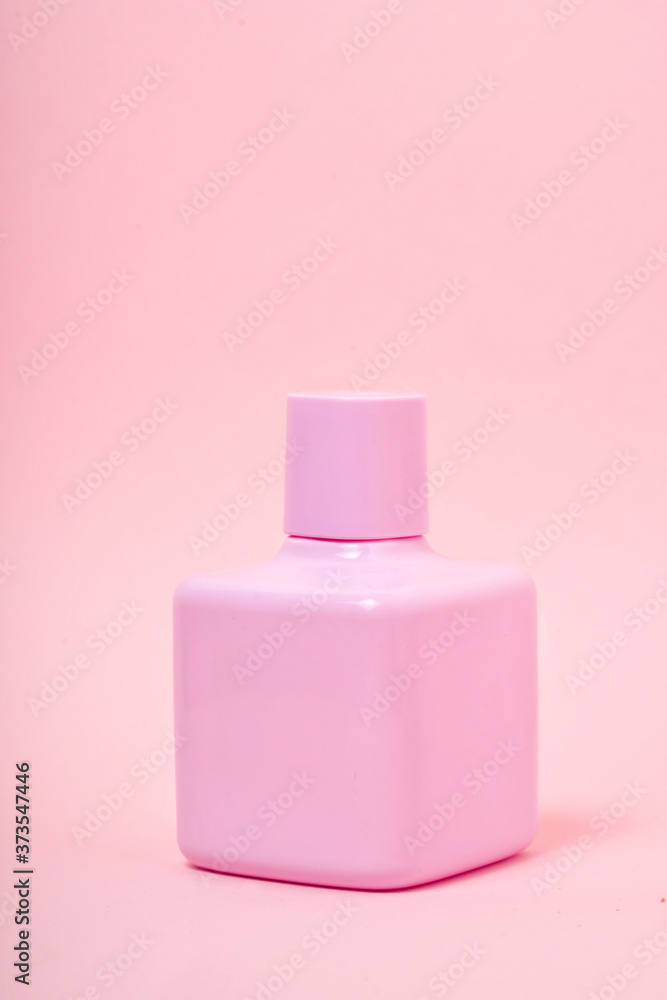 Bottle of pink perfume on color background. Beautiful cosmetics packaging design concept with liquid soap or shower gel on a soft pink background. Summer mood Bottle of pink perfume on color background. Beautiful cosmetics packaging design concept with liquid soap or shower gel on a soft pink background. Summer mood