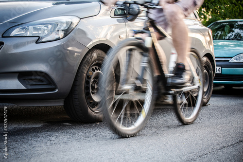 Foto An unidentified man riding a bicycle passing cars on the road in the traffic