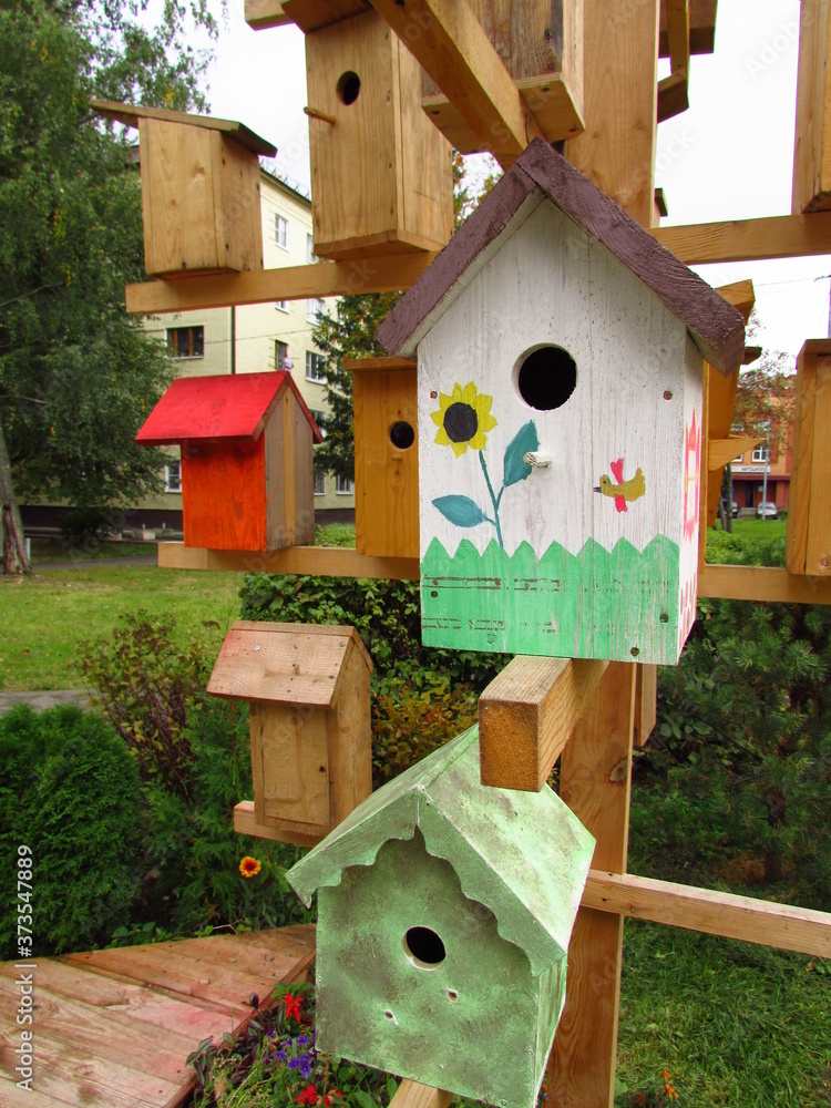 Many birdhouses are hung on a wooden structure that imitates a tree. Some of them are painted. Vertical photo Many birdhouses are hung on a wooden structure that imitates a tree. Some of them are painted. Vertical photo