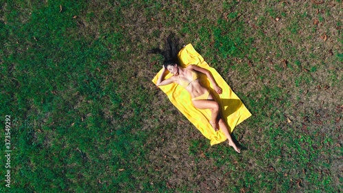 woman in bikini lying on a meadow shot by a drone