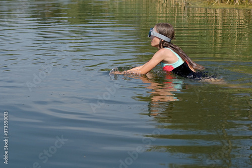 Fototapeta Naklejka Na Ścianę i Meble -  a young girl swims in the lake