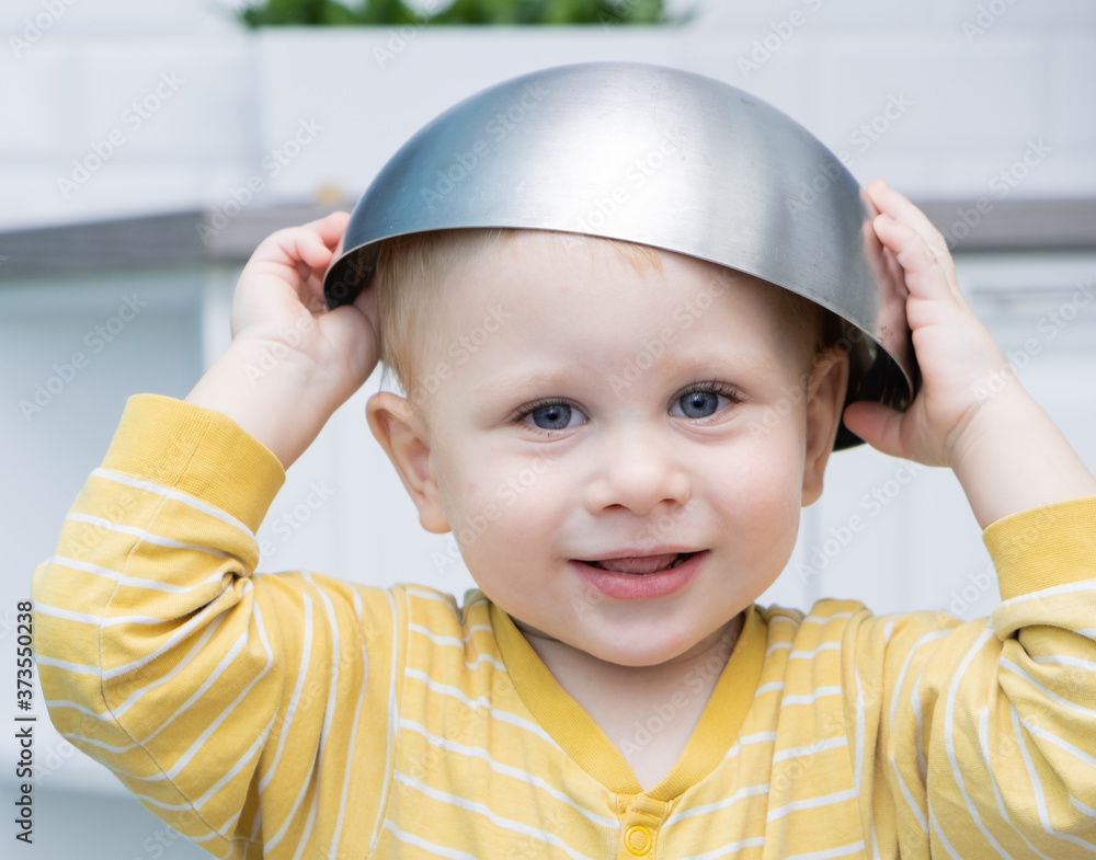 boy smiling with a bowl on his head. games in the kitchen. boy smiling with a bowl on his head. games in the kitchen.