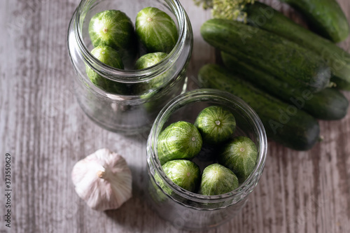 Preservation, conservation. Pickled, pickled cucumbers in a jar on a wooden table. Cucumbers, herbs, dill, garlic. Rustic. Background image, copy space, horizontal.