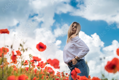 Fototapeta Naklejka Na Ścianę i Meble -  Beautiful young woman walking in poppy field on  summer day