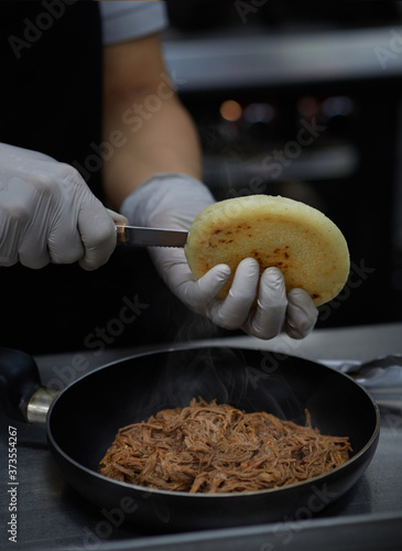 chef preparing Venezuelan arepa stuffed with shredded meat typical food photo